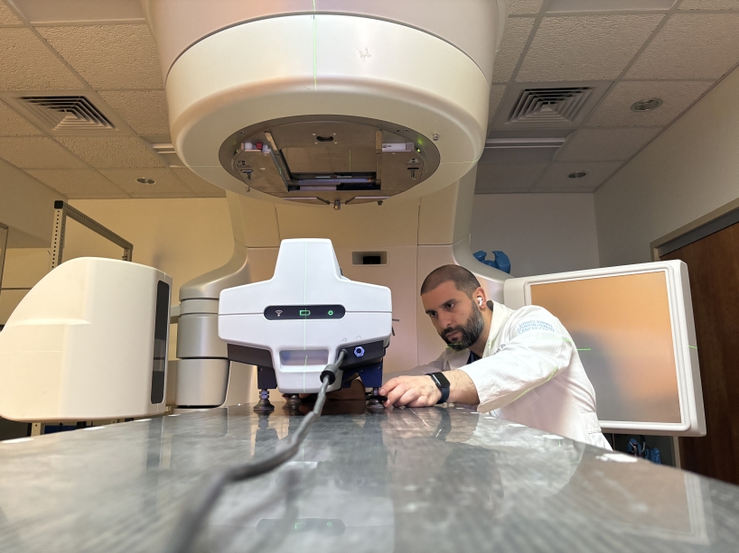 A man in a white coat looks at scientific equipment in a lab.