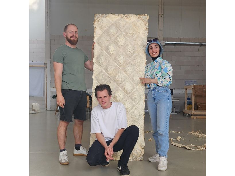 Allataifei standing next to collaborators assembling a large mycelium panel in Stuttgart, Germany.