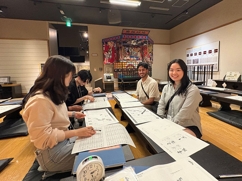 Four people sit at a table with papers and pens.