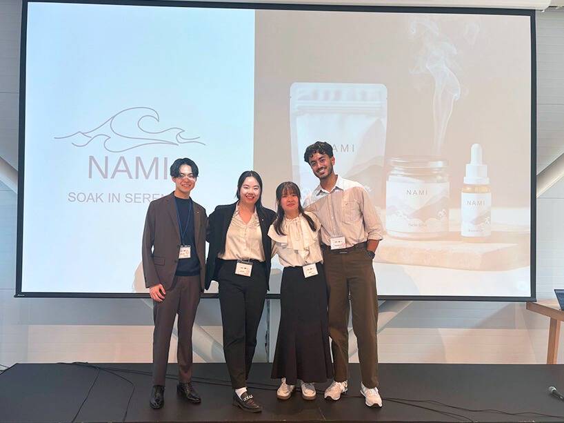 Four students wearing business clothes pose for a photo after giving a presentation.