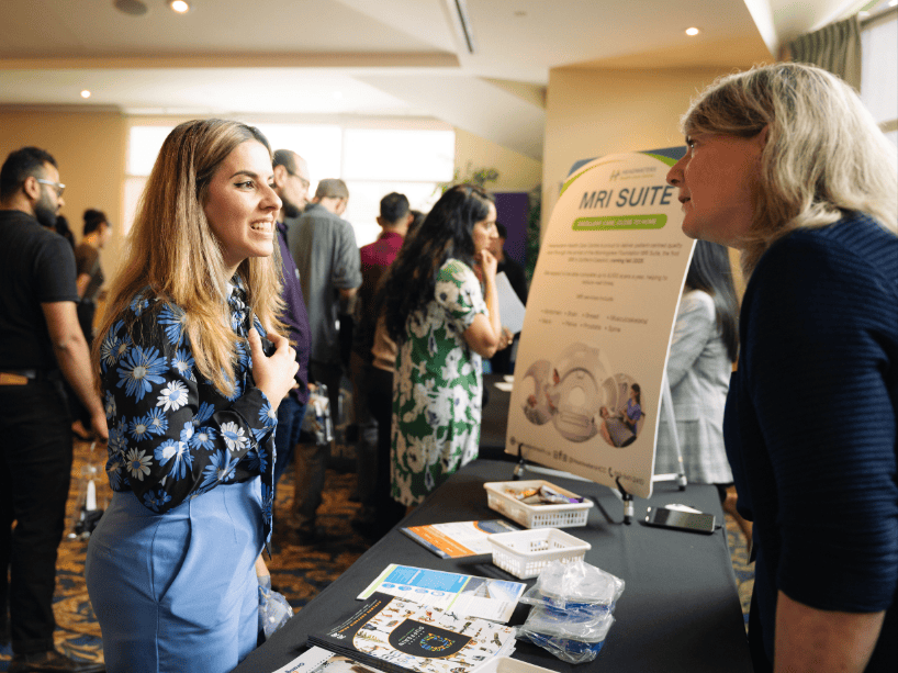 A woman speaking with someone at a booth.