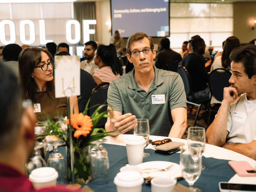 A group of people sitting and chatting at a table.