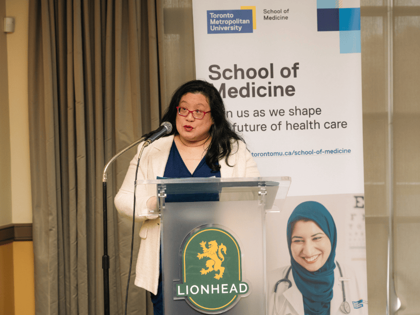  A woman speaking at a podium to a crowd.