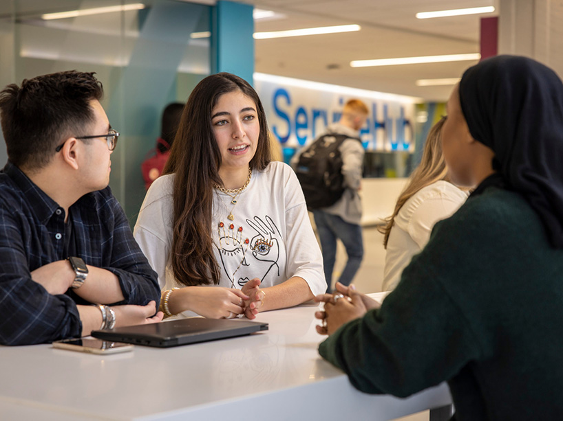 A group of students hanging out on the blue staircase in the Sandbox by DMZ in the SLC.