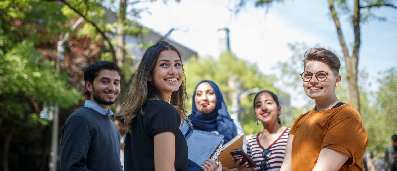A group of students smile together on campus.