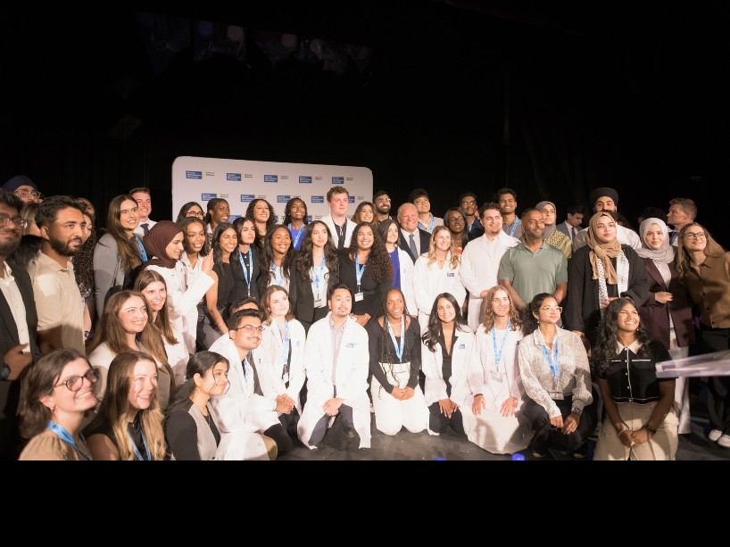 Inaugural class gathered on stage, smiling. 