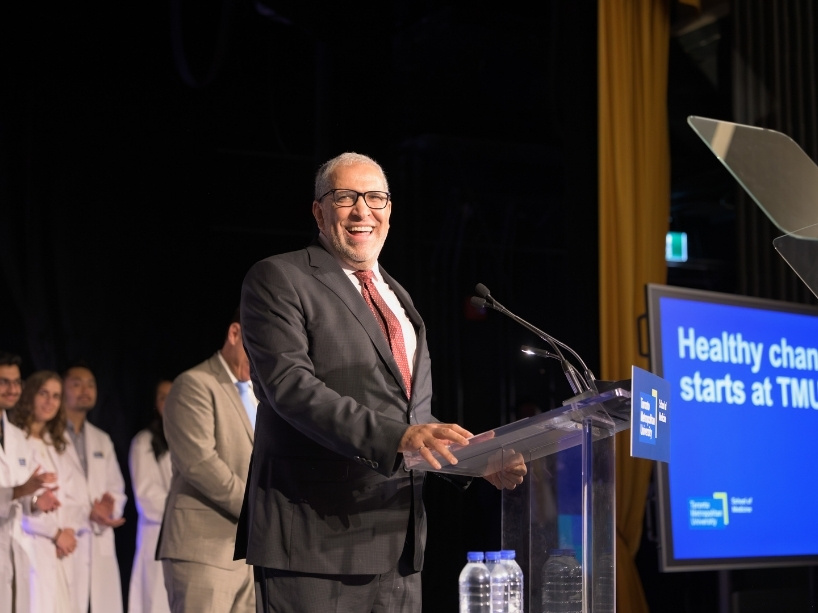 Mohamed Lachemi at a podium, with a group of med school students behind him.