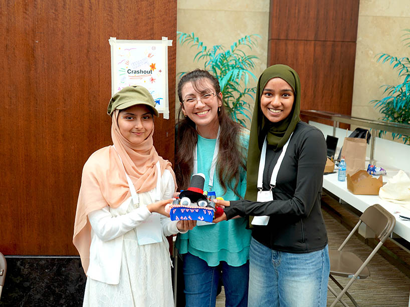 Three people posing for a photo with their robot.