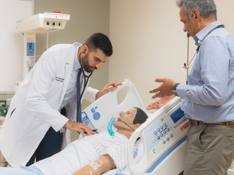 Dr. Christopher Haddad learns using a medical mannequin along with a clinical faculty member.