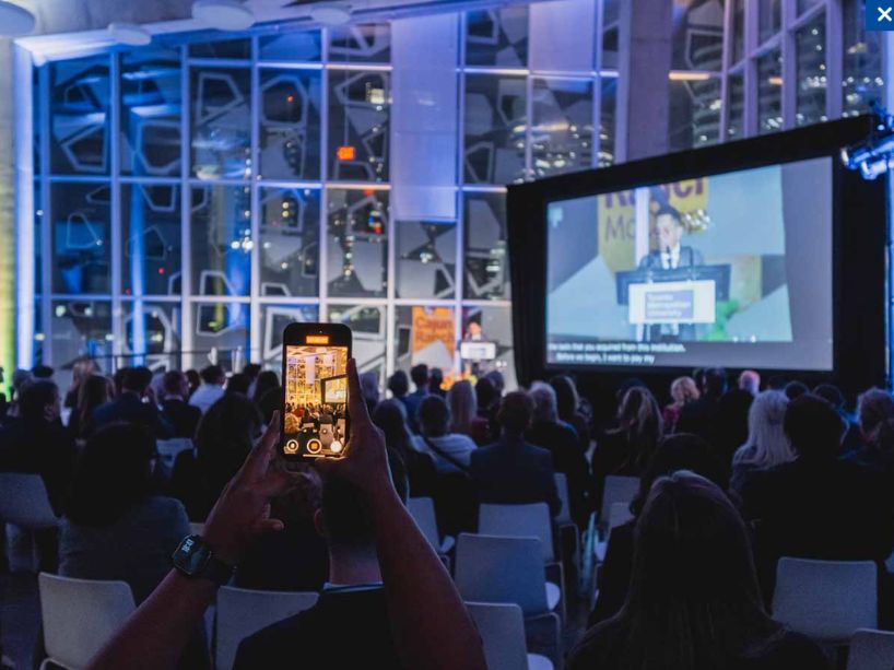 Guest takes a cell phone photo of a speaker at the awards event