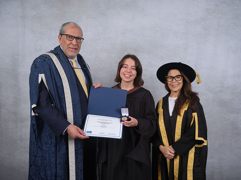 Two people in academic regalia pose for a photo.