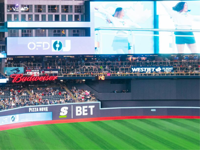 Baseball stadium event shows advertising on stadium panels for an online gaming app.