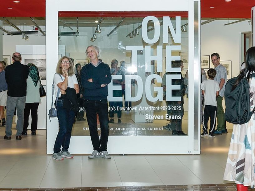 Viewers of the exhibition roam the space observing the photographs.