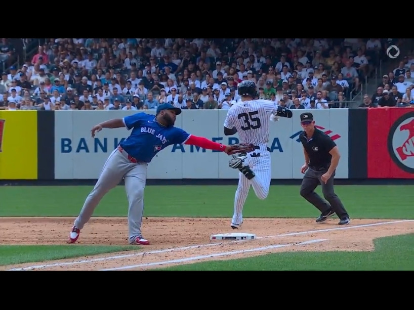A baseball player tries reaches out with his glove to try and get the opposing player 'out' at one of the bases.