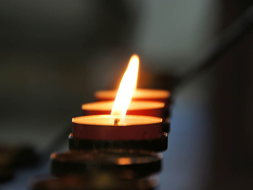Small candles placed in a row shine brightly in the dark.