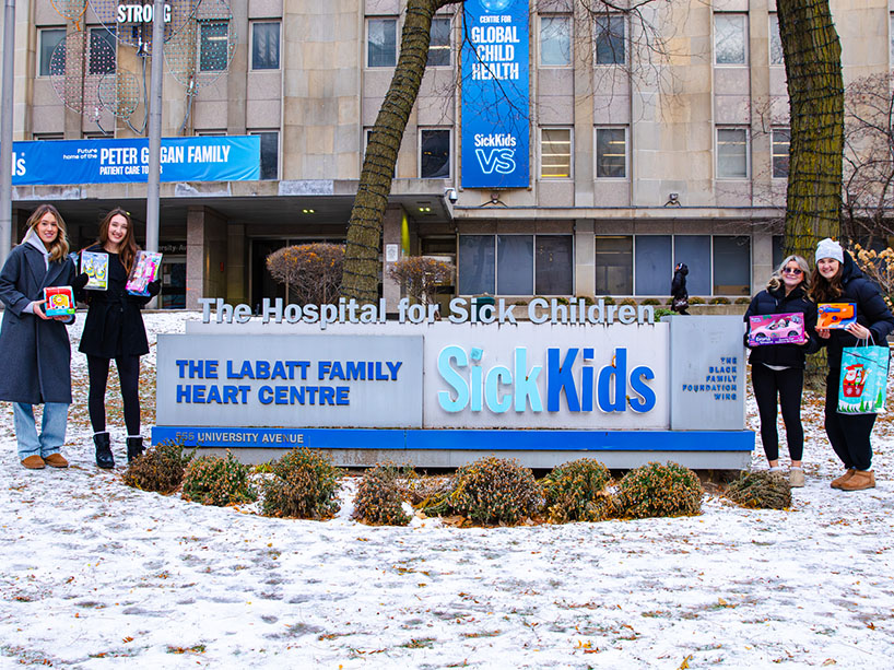 Four students pose in front of the SickKids hospital sign.