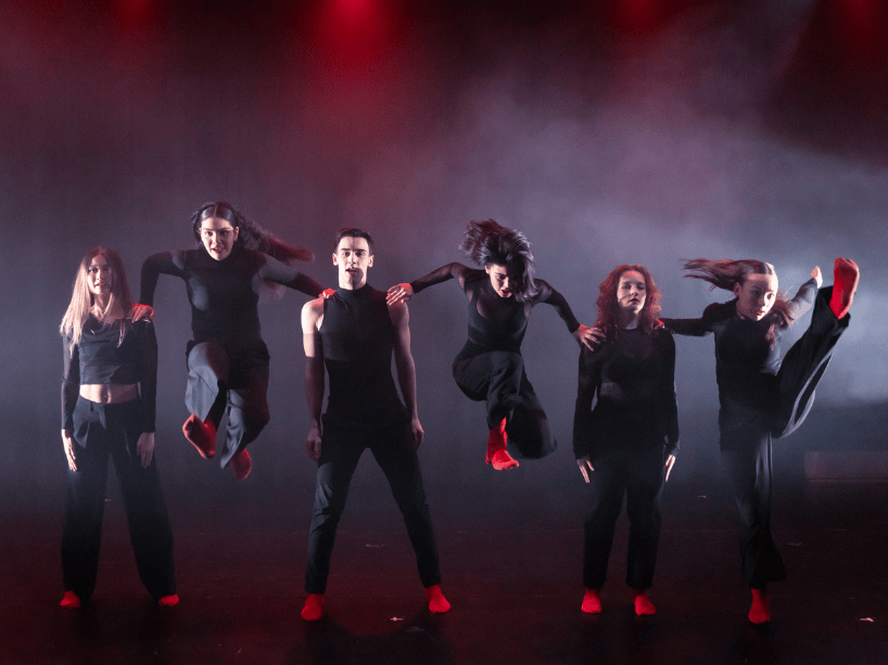 Photo of six dancers wearing black.