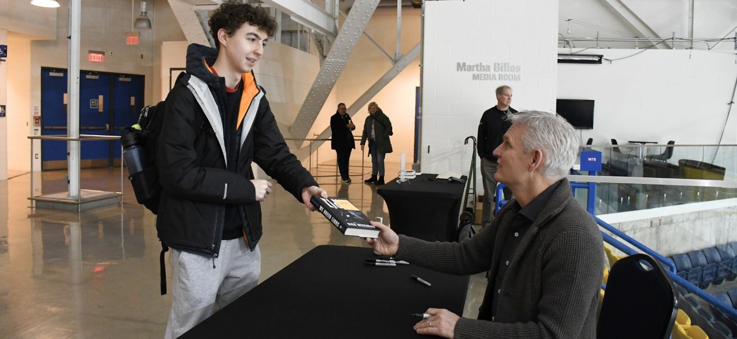 A young man hands Rick Westhead a copy of his book to sign.