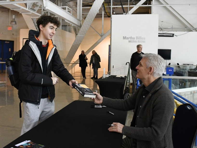A young man hands Rick Westhead a copy of his book to sign.