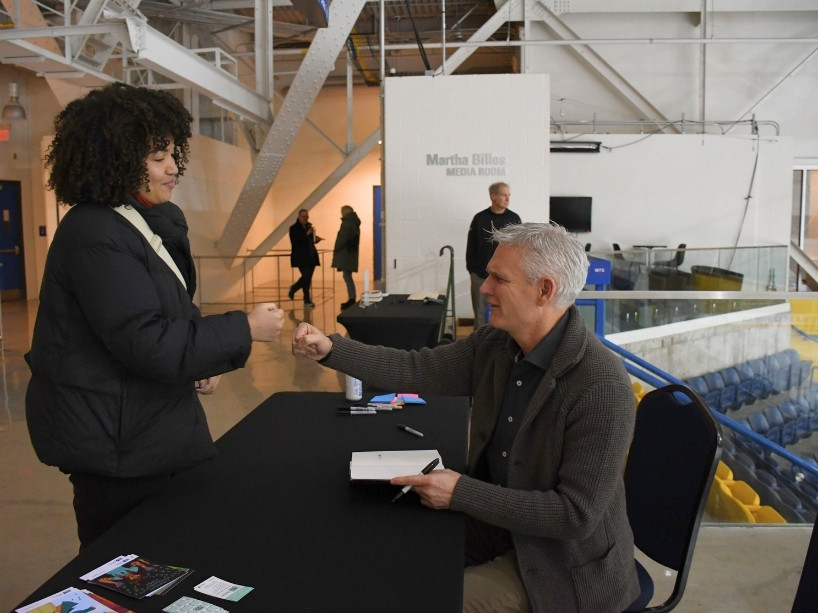 A female student fist bumps with Rick Westhead as he signs a copy of his book.