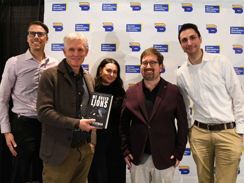 Four people pose for a photo with Rick Westhead, who holds a copy of his new book.