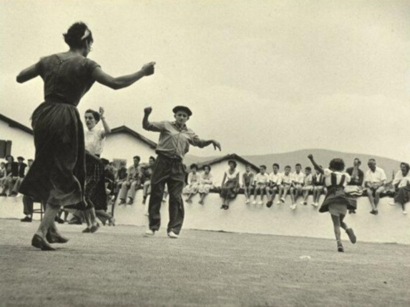 Young people play and dance in a courtyard in this black and white photo from 1951.
