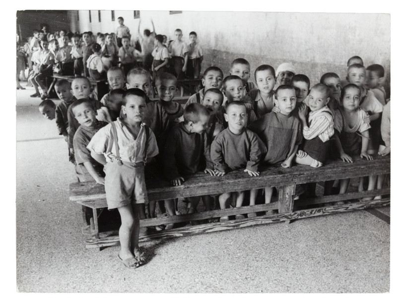 Dozens of children huddled together in pews pose for the camera in this 1948 photo taken in an orphanage.