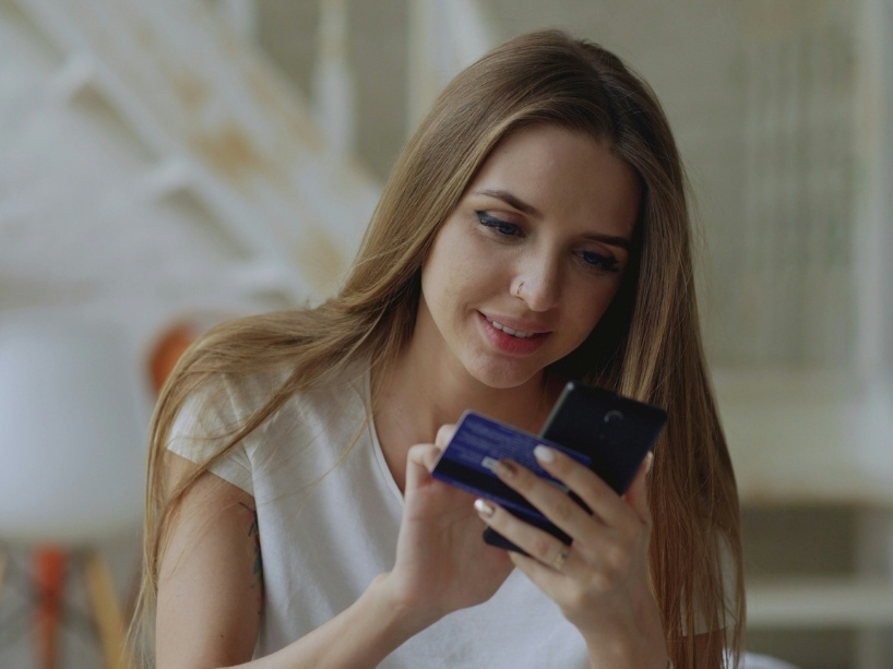 Young woman on a cell phone making an online purchase with a payment card.