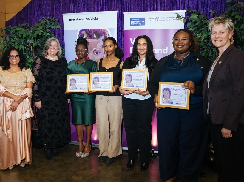 A group of award recipients hold their awards, stand together with TMU leaders.