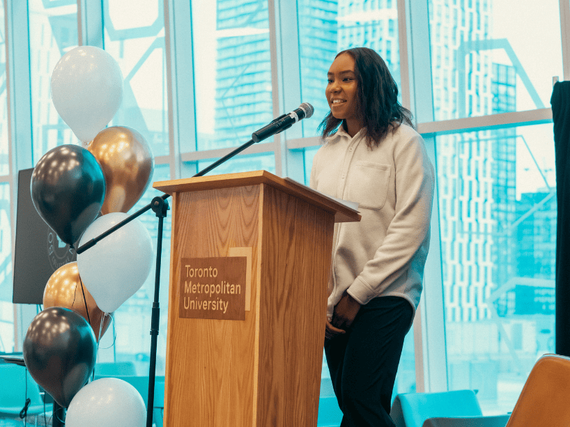 Gabrielle Solano speaking at podium.