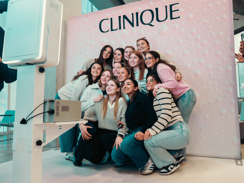 Group of women pose in front Clinique sign.