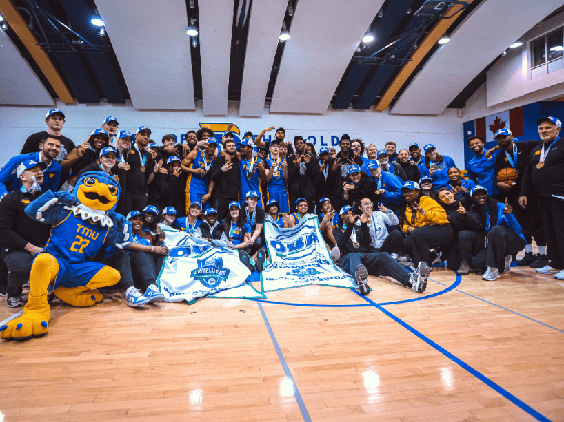 A large group of male and female basketball players pose for photos while celebrating their championship wins.