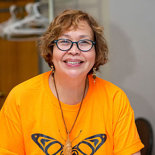 A portrait photo of Monica Mckay smiling in an orange t-shirt.