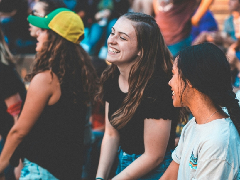 Two girls smile among a crowd. 
