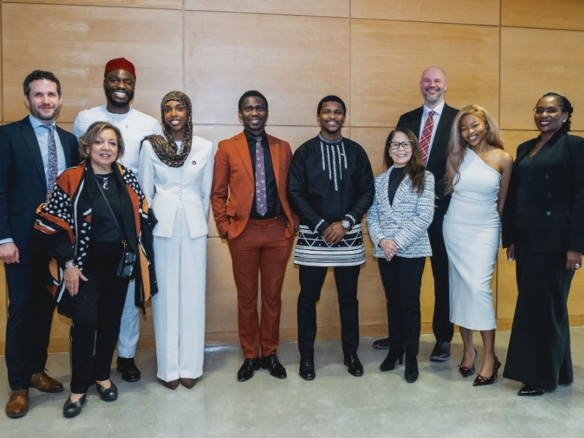 Siyabulela Mandela pictured standing with TMU Chancellor and event organizers in front a wood-panelled wall at the Sears Atrium on campus.