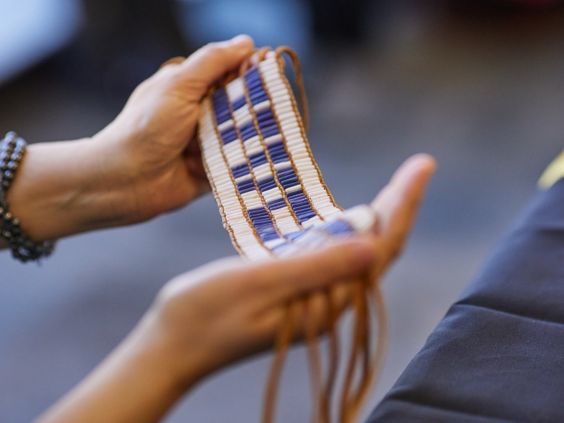 Two hands holding a replica of a Wampum belt. 