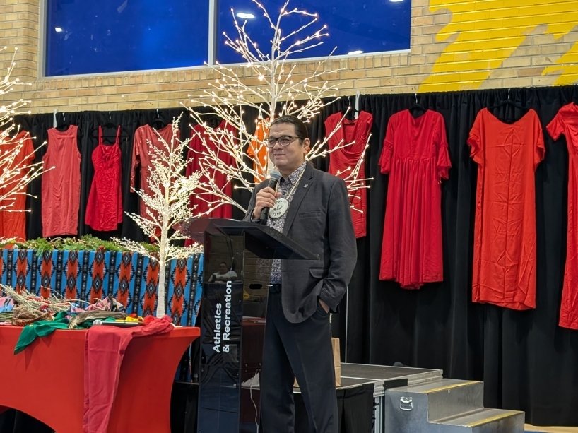 Duke Peltier standing at a podium holding a microphone. 