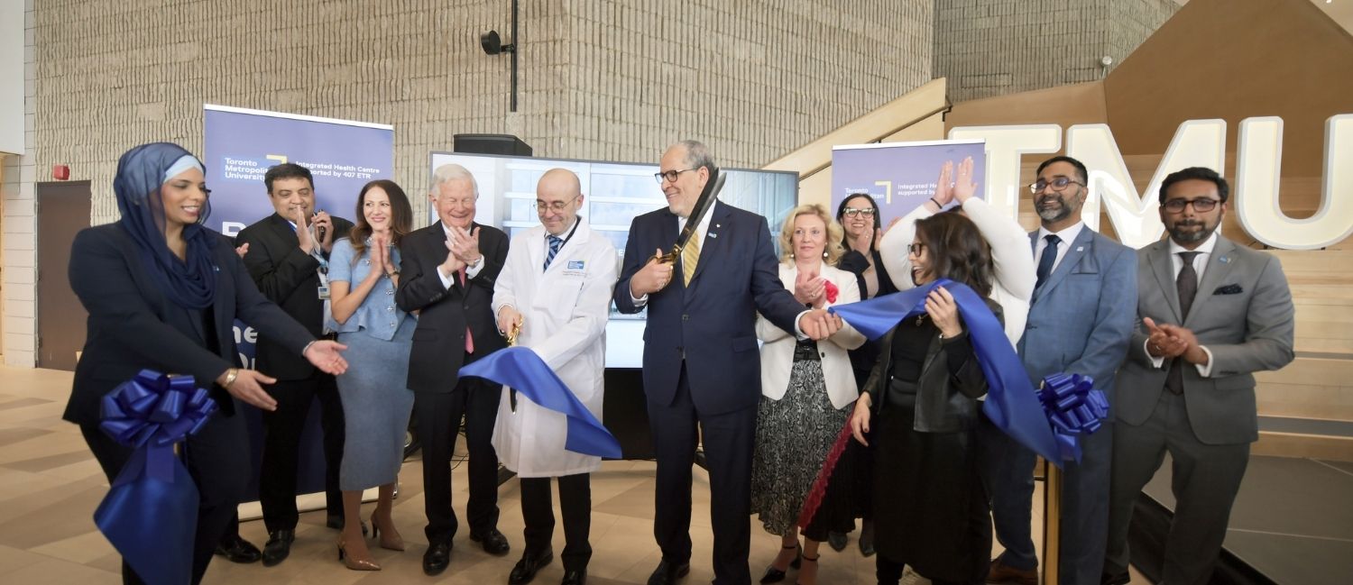 A group of people celebrate at a ribbon-cutting ceremony.
