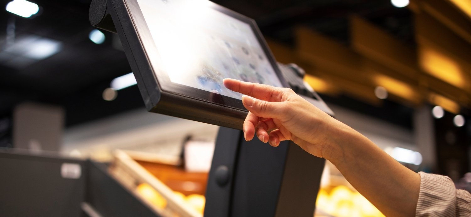 A shopper scans though a bunch of bananas at a self-checkout kiosk.