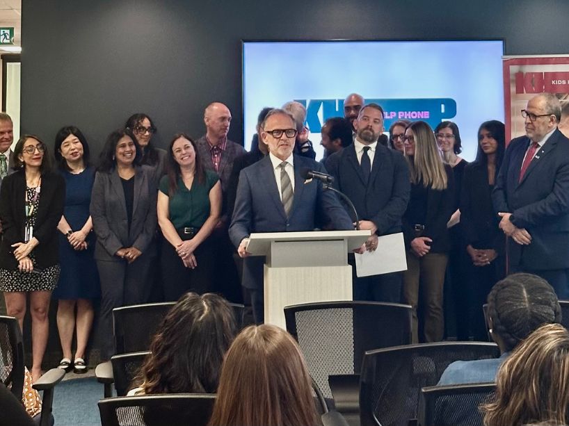 Steven N. Liss, TMU’s vice-president, research and innovation, speaking at the announcement event. Mohamed Lachemi, TMU’s president and vice-chancellor, as well as TMU researchers and Kids Help Phone researchers and executives are standing in the background.