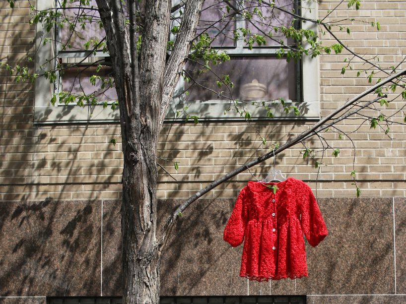 A child’s red dress hangs from a tree on TMU campus.