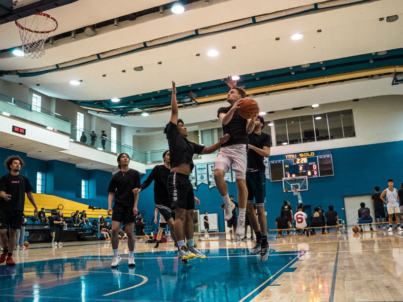 A group of people playing basketball on a court.