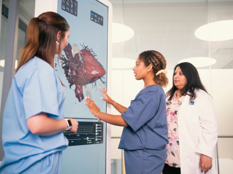 Nursing students and professor using a digital anatomy table to learn about the human body, study the human heart.