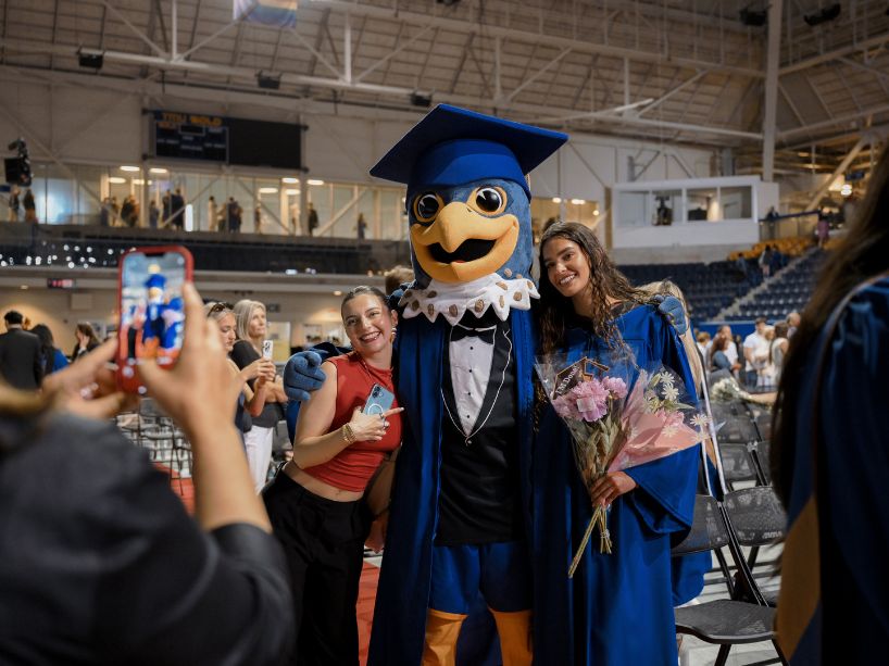 Two students posing with Frankie the Falcon.
