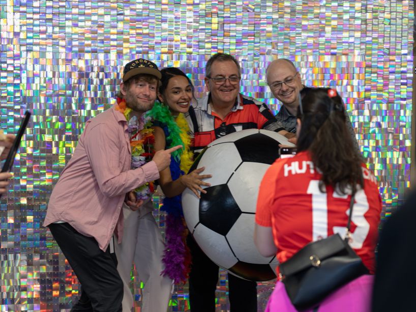 A group of people posing with a large soccer ball.