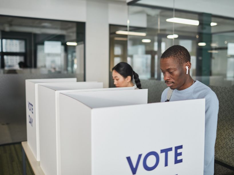 Two people behind voting boxes.