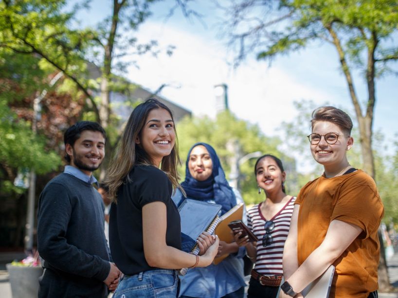 A group of five students smiling on Gould St. on campus.