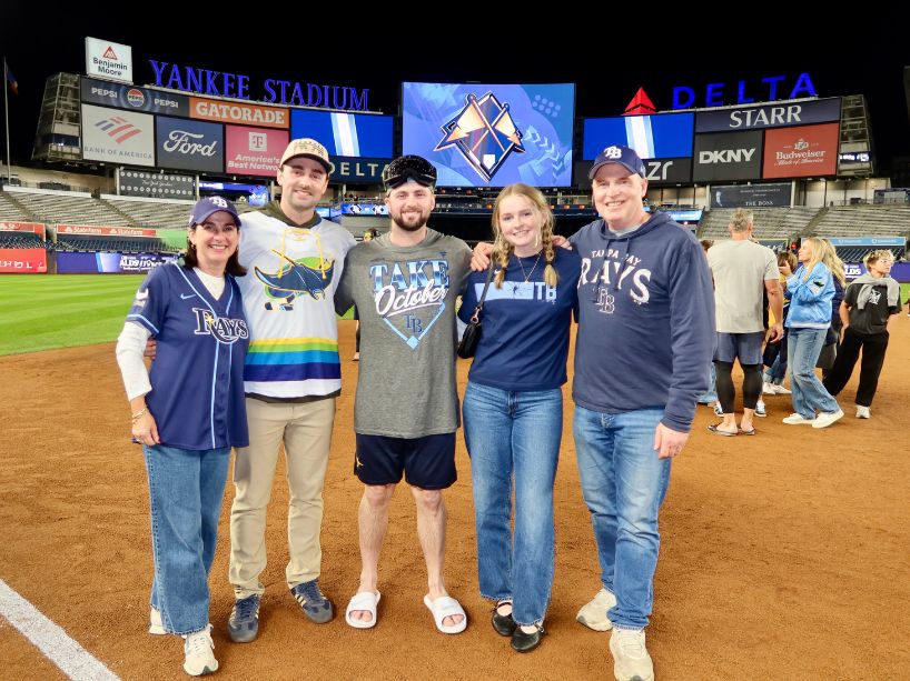 Hicks family posing on baseball field.