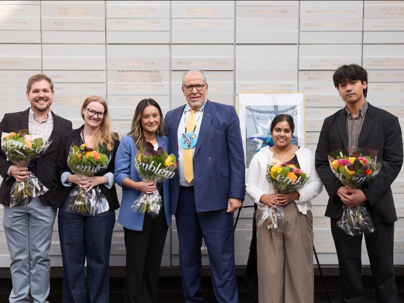 Team members Kim McDonald, Jessica Tran, Ryan Kerr, Jordan Luu and Daneese Rao standing with President Lachemi, smiling, holding bouquets of flowers.