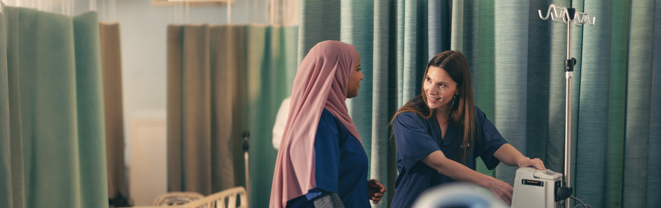 A pair of Nursing students chat while setting up an IV pole.